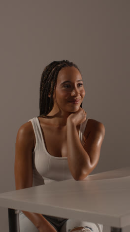 Studio-Beauty-Shot-Of-Young-Woman-With-Long-Braided-Hair-Sitting-At-Table